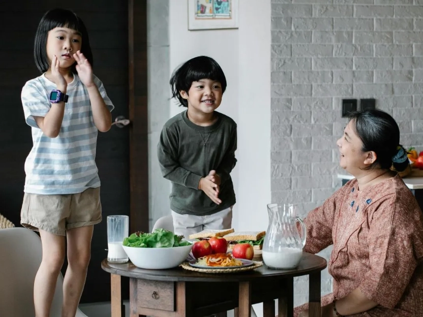 Uma família desfruta de uma refeição saudável, com pratos que incluem verduras e leite, representando as diversas fontes de cálcio na dieta familiar.