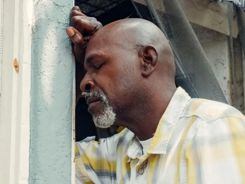 Homem encostado na parede com semblante cansado, representando efeitos da carência de cálcio.