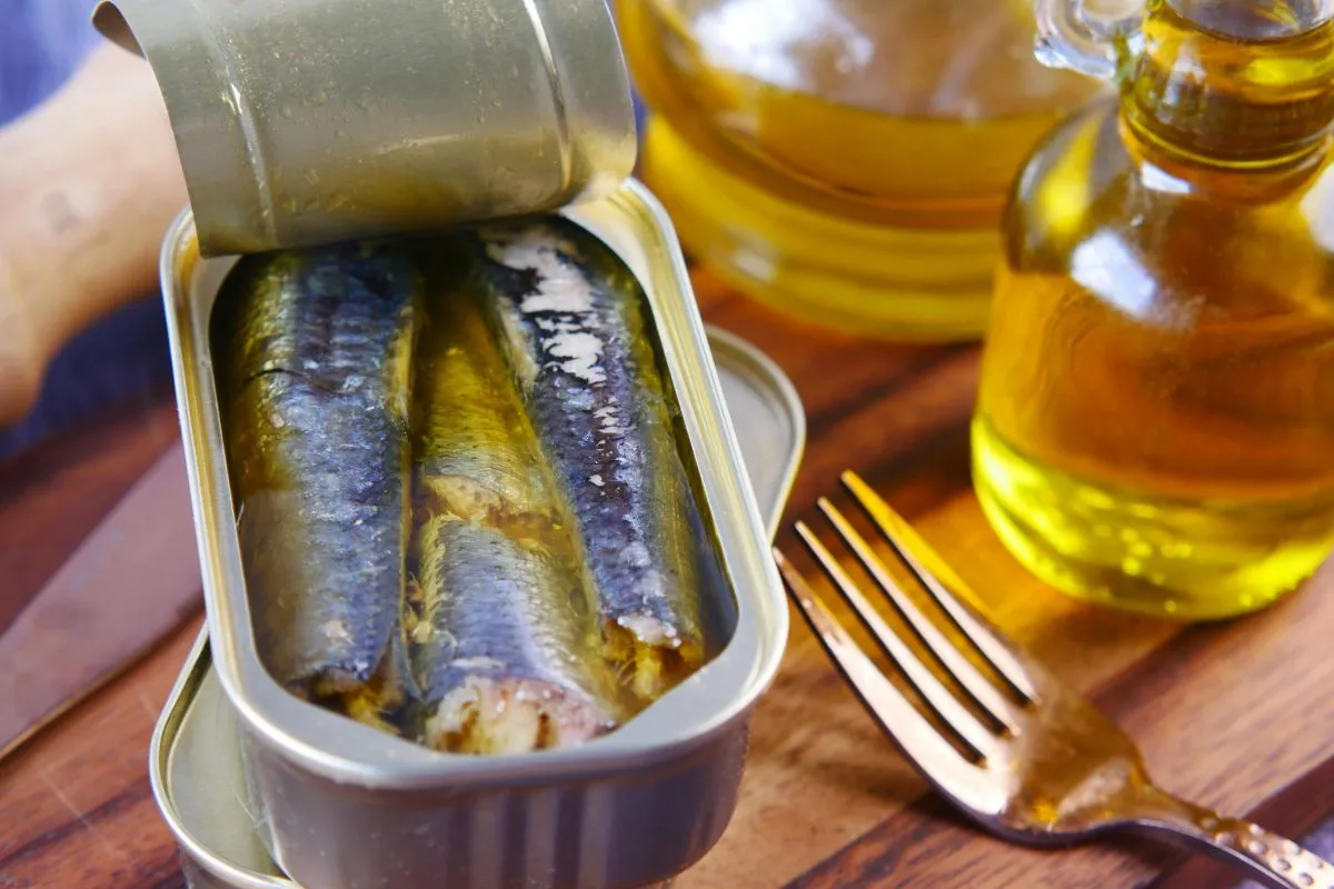 Uma lata de sardinhas abertas sobre uma mesa, mostrando um alimento rico em cálcio e outros nutrientes essenciais, ideal para uma dieta equilibrada.